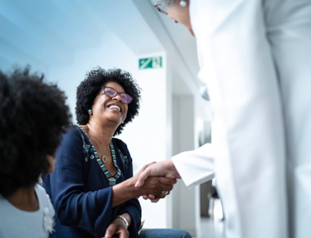 Smiling woman shakes hands with her doctor.